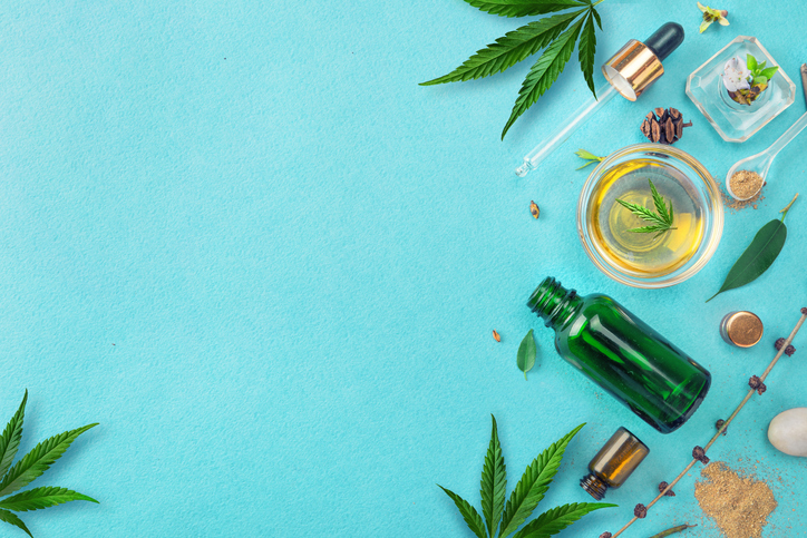 Glass bottles with CBD oil, THC tincture and hemp leaves on blue background. Flat lay, minimalism. Cosmetics CBD hemp oil. extracts