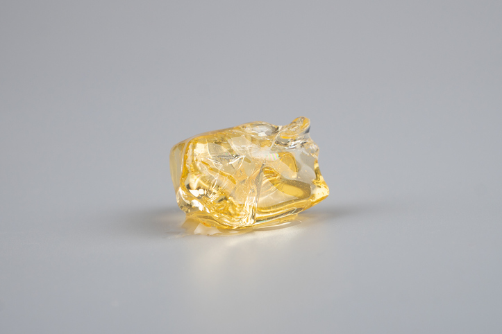 yellow piece cannabis resin concentrate on gray background. high thc diamond liquiddiamondsweed
