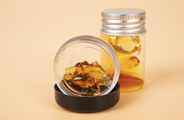 yellow extract wax from cannabis buds in container, marijuana thc distillate Live Resin diamonds