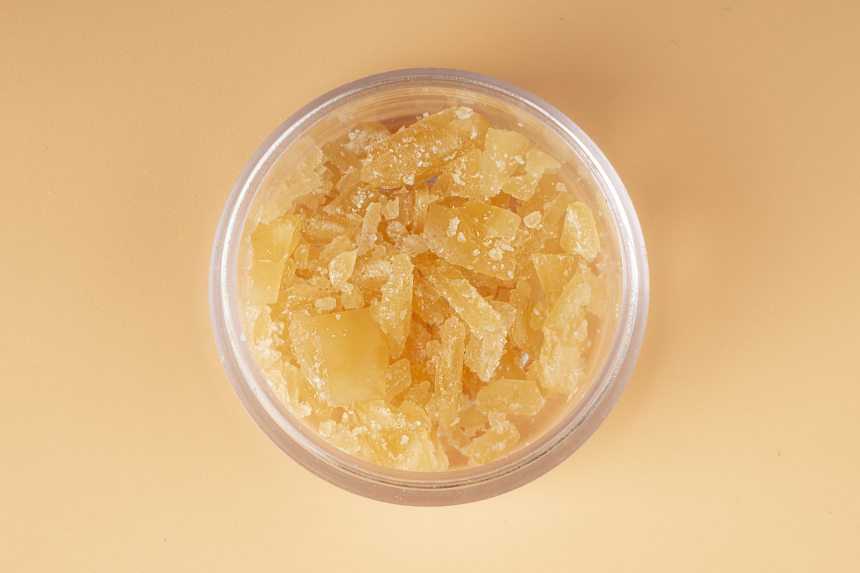 glass jar with golden cannabis wax, pieces of hardened resin of marijuana extract on an orange background how are diamonds extracted