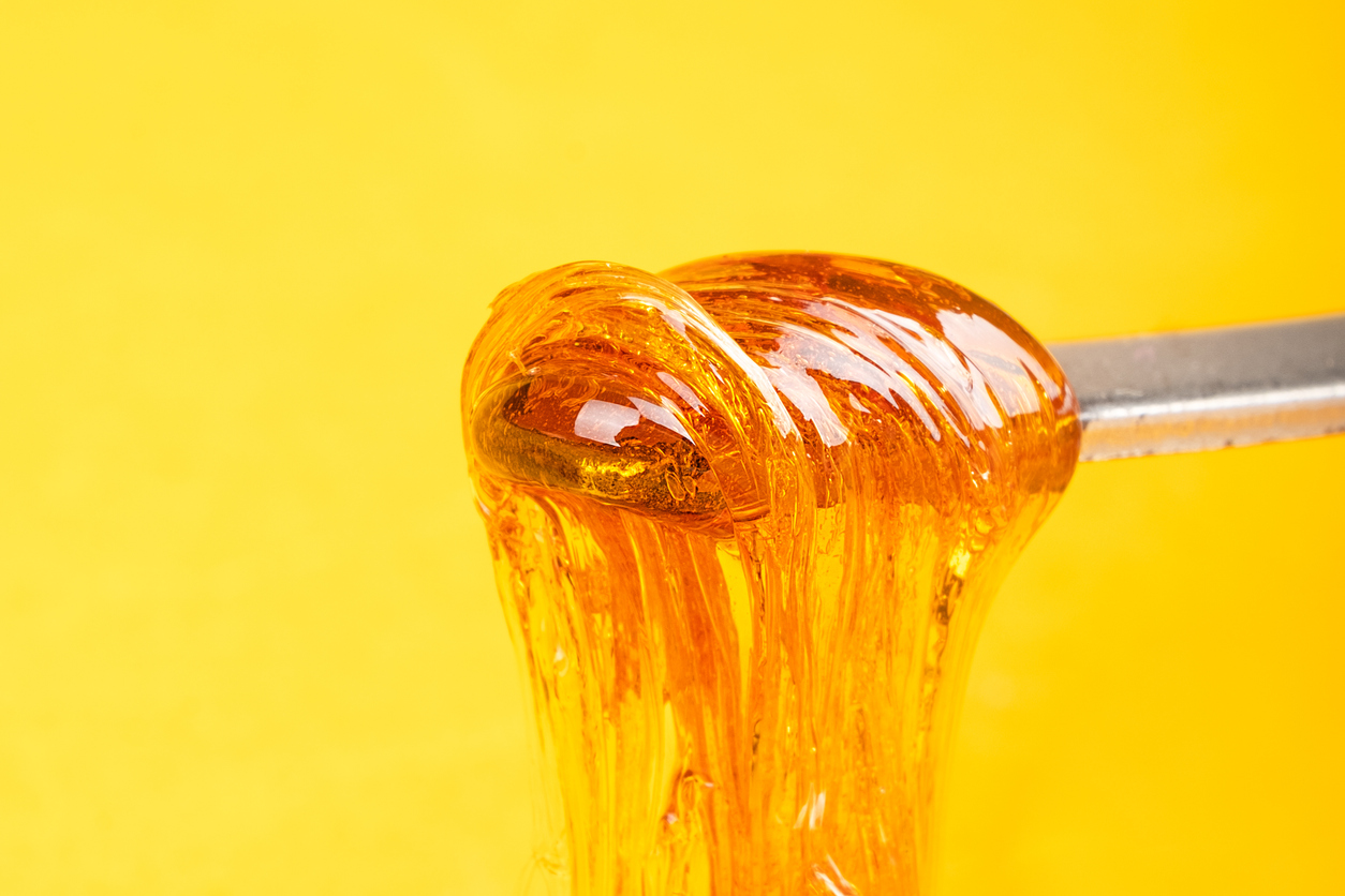 amber yellow cannabis wax concentrate dripping from the dabbing tool close-up what is thc badder